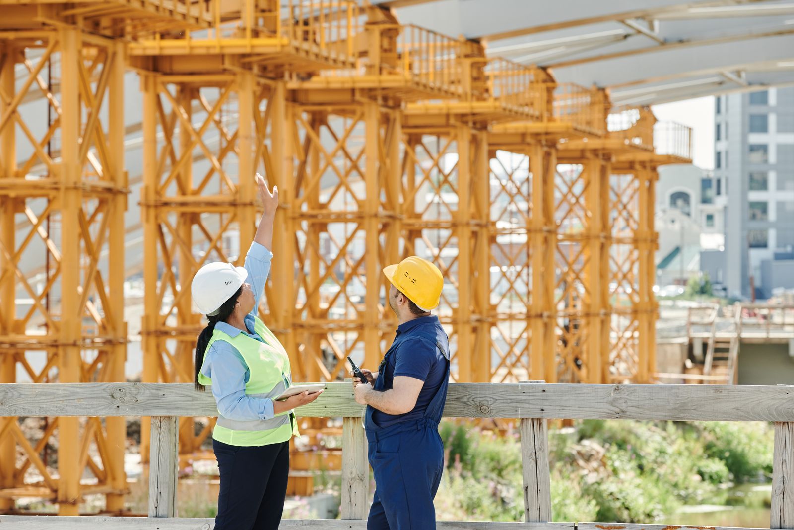 Two professionals reviewing plans on a tablet at an industrial site